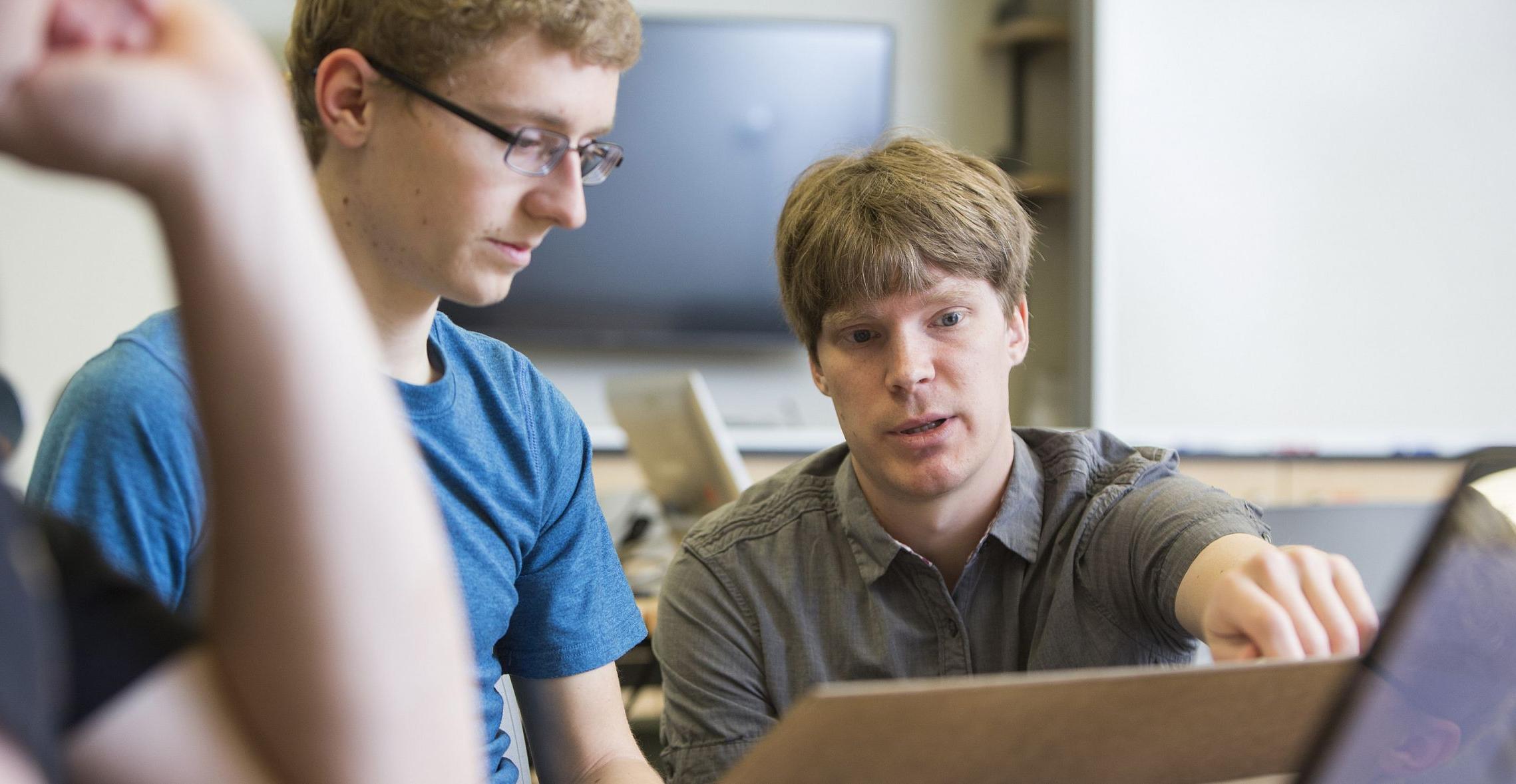 Prof. Brant Carlson assists a physics major student during a physics class.